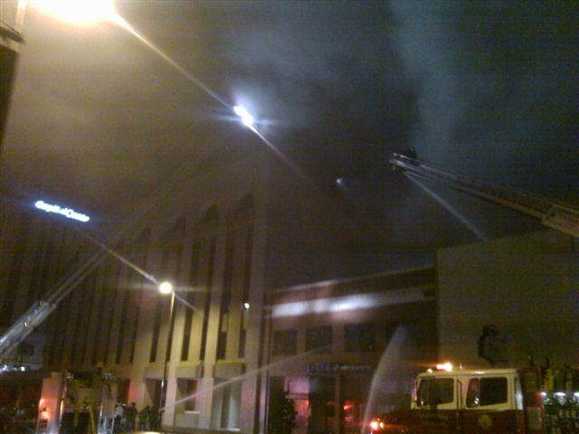 Fire trucks extend their ladders to spray water down on the fire.